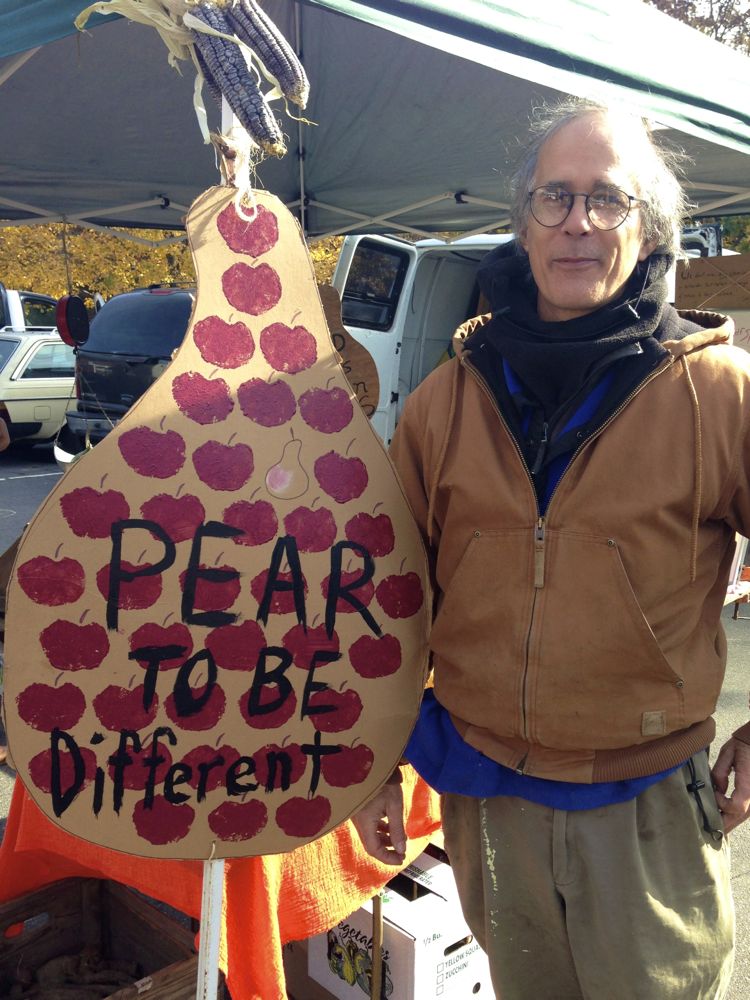 Bill Whipple holds a large, pear-shaped cardboard sign that says "Pear to be Different".