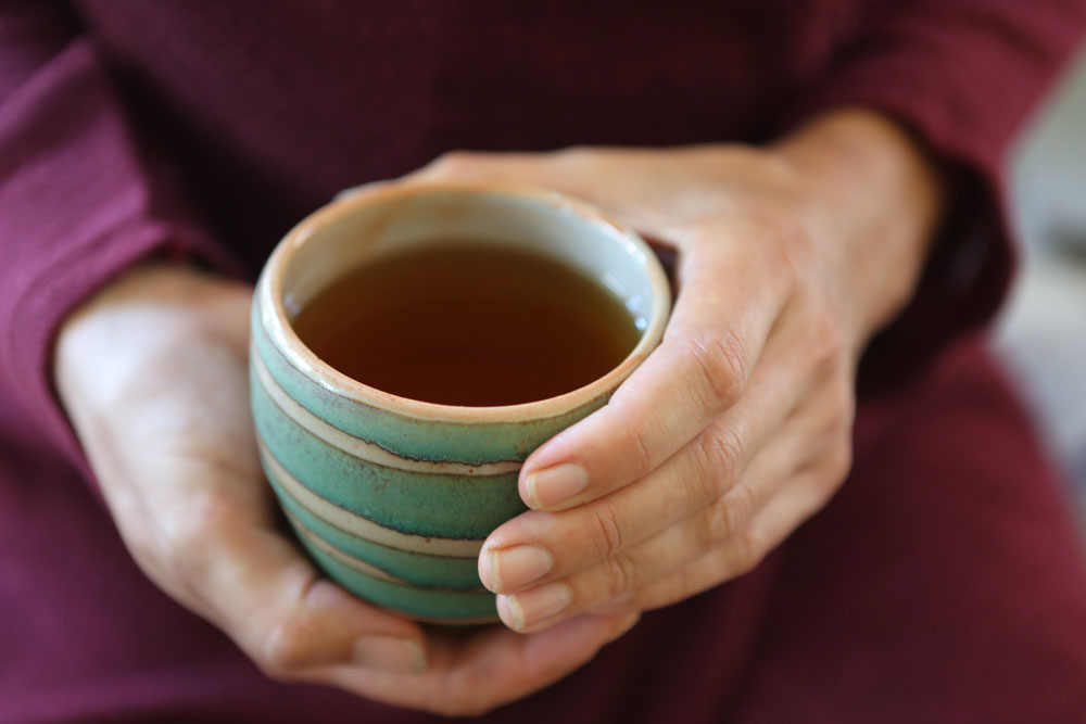 Hands holding a mug of tea.