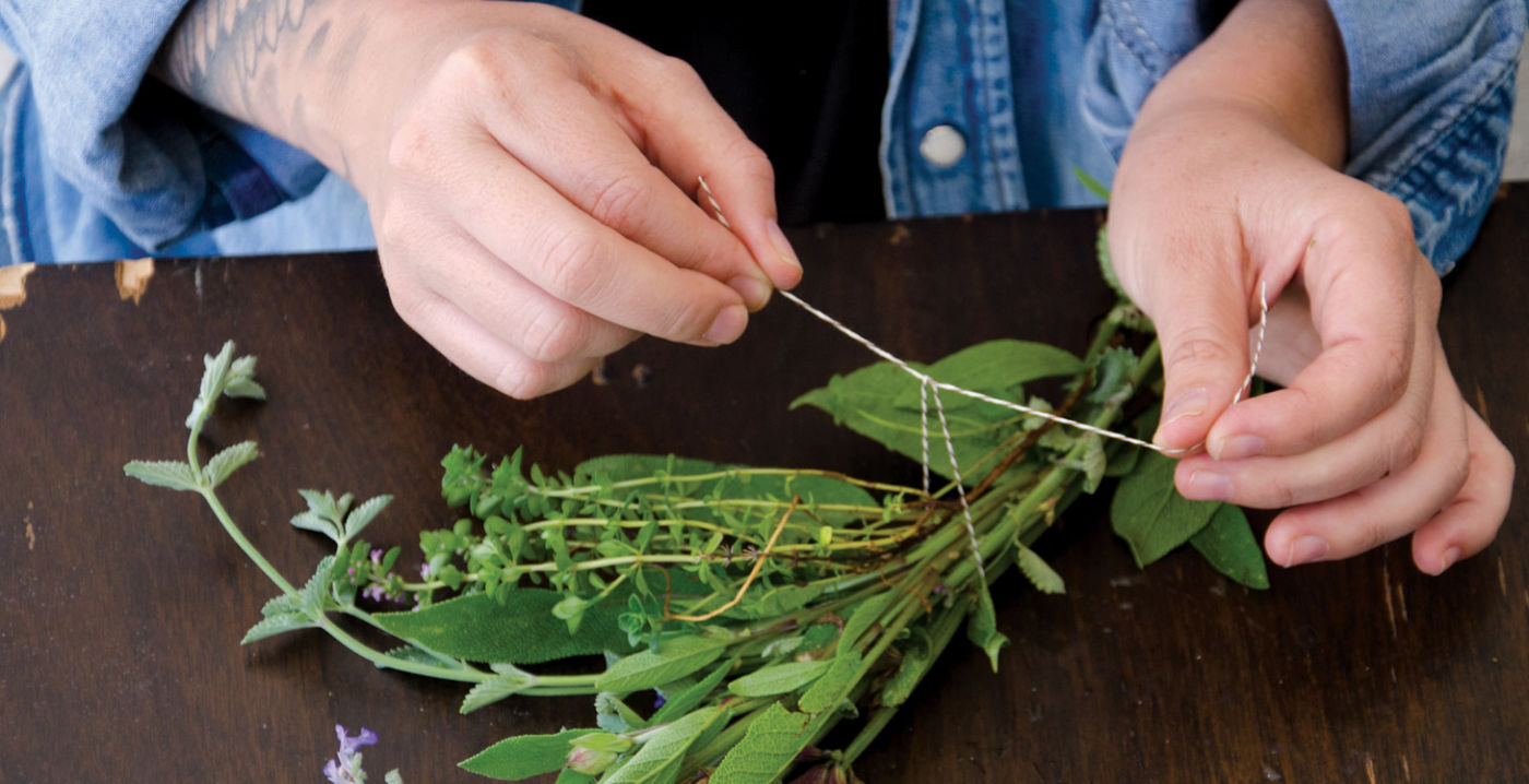 Step 3: Snip several stems of sage, chives, thyme, marjoram, lavender, and any other herbs you have. Tie the small bunches of herbs together and secure them to the rosemary frame with twine.