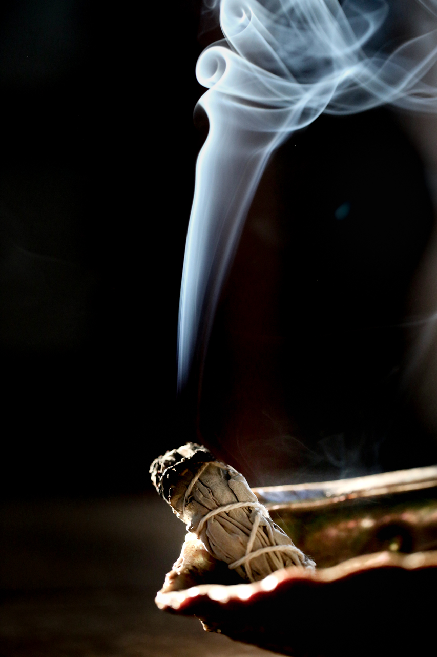 Smoldering aromatic smoke stick resting in an abalone shell.