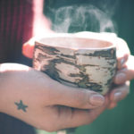 Someone holds a cup of steaming tea.