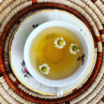A full teacup of Balm in Gilead Tea with floating flowers.