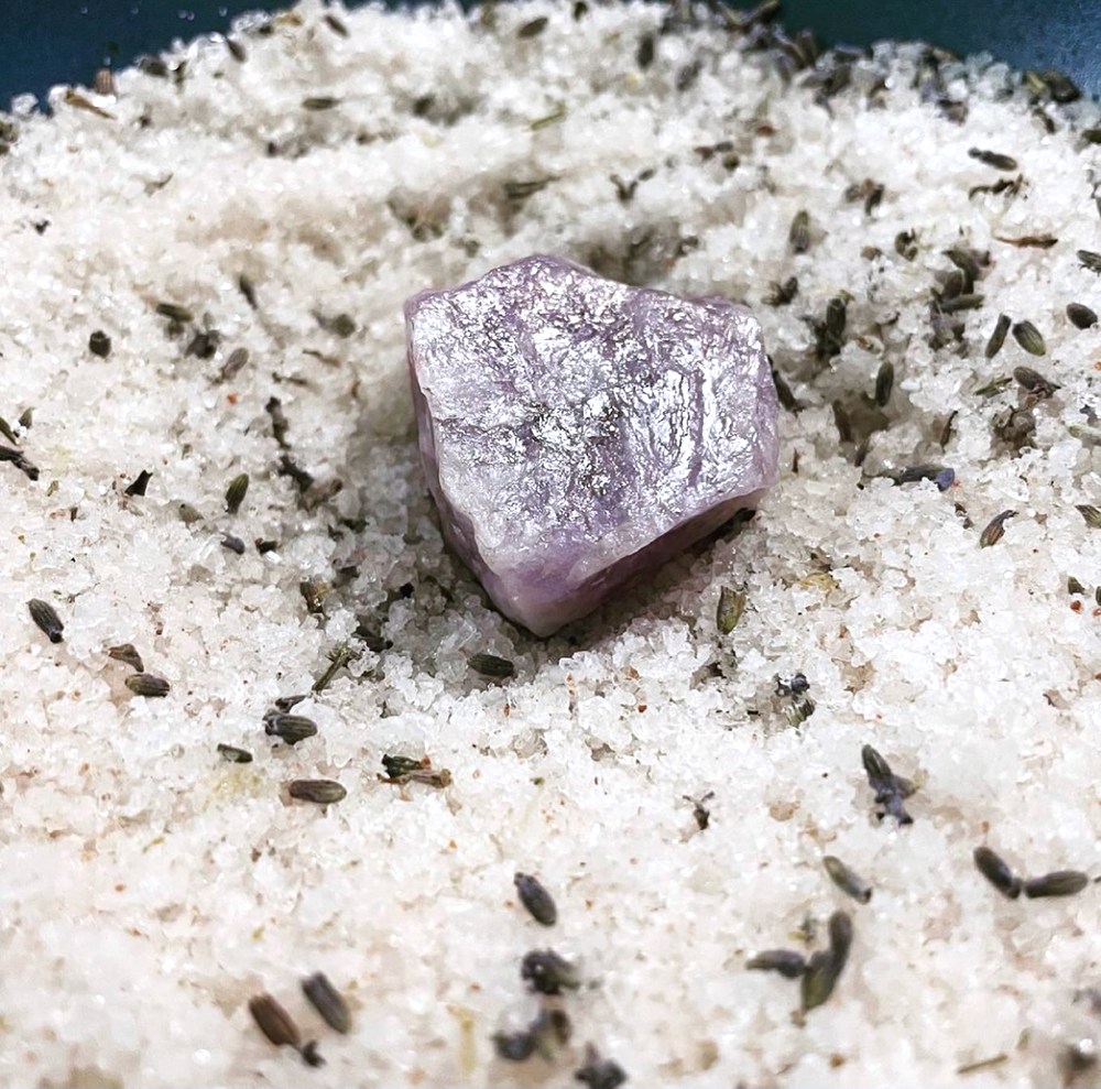 An amethyst on a pile of herbal bath salt.
