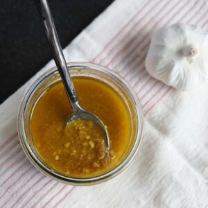 A spoon sits in a small jar of medicinal garlic sauce.